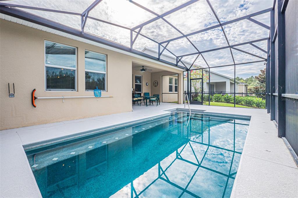A screened-in patio features a rectangular swimming pool and a covered outdoor seating area — 10174 LOVEGRASS LANE, ORLANDO, FL