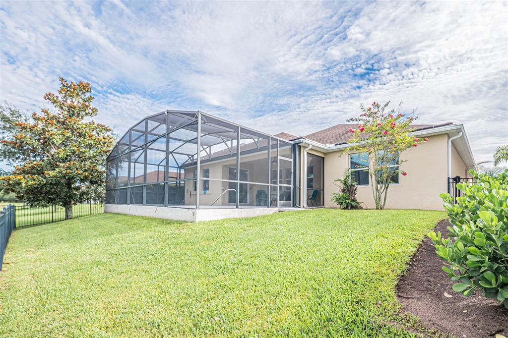 A backyard view of a house with a screened-in patio and a grassy lawn — 10174 LOVEGRASS LANE, ORLANDO, FL