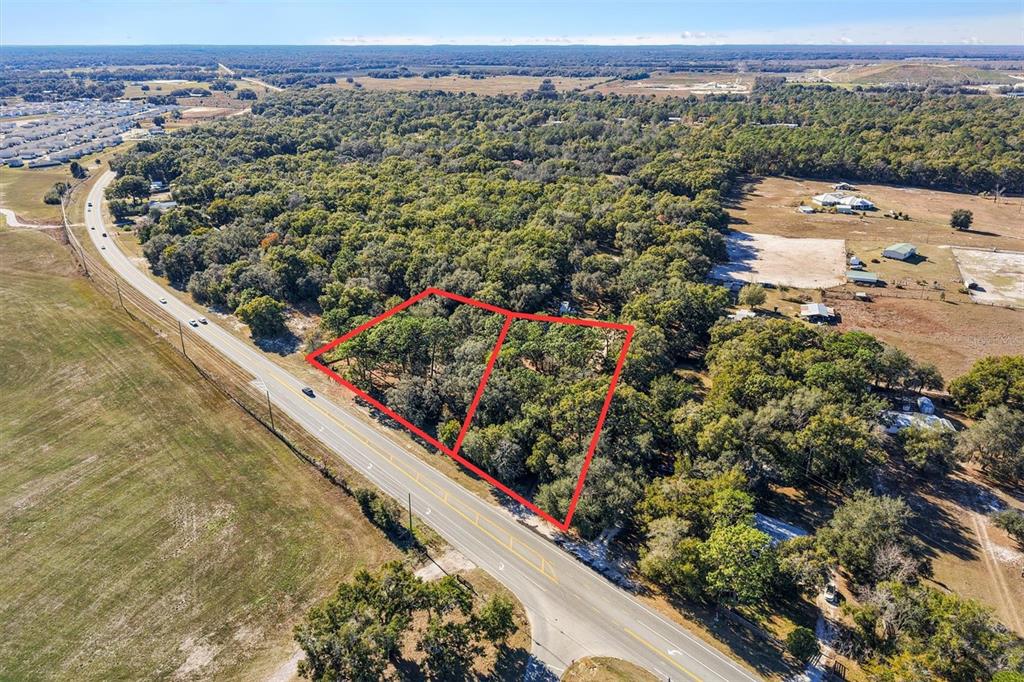 An aerial view shows two adjacent wooded lots outlined in red along a paved road — 00 S US 301, SUMTERVILLE, FL