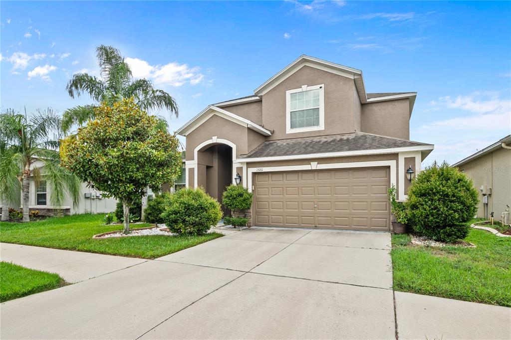A two-story suburban house with a tan stucco exterior and a two-car garage — 13161 ROYAL PINES AVENUE, RIVERVIEW, FL