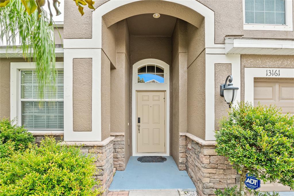 The exterior of a house features a tan front door, stone accents, and a covered entryway — 13161 ROYAL PINES AVENUE, RIVERVIEW, FL