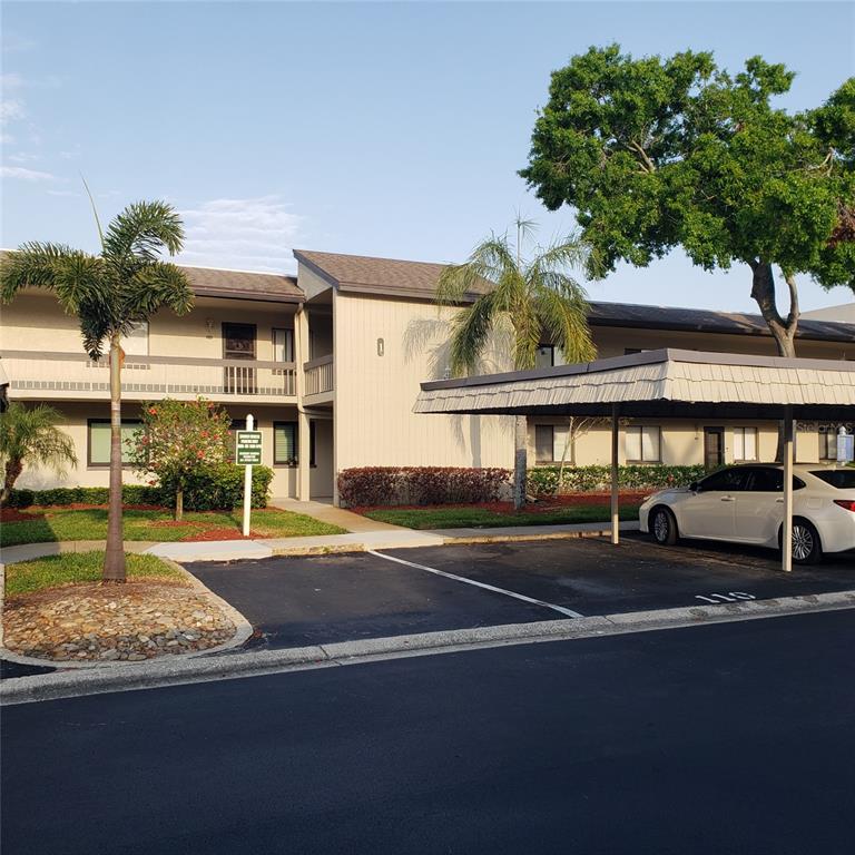 A two-story apartment building with a covered parking space and palm trees in front — 113 NINA WAY UNIT 113, OLDSMAR, FL