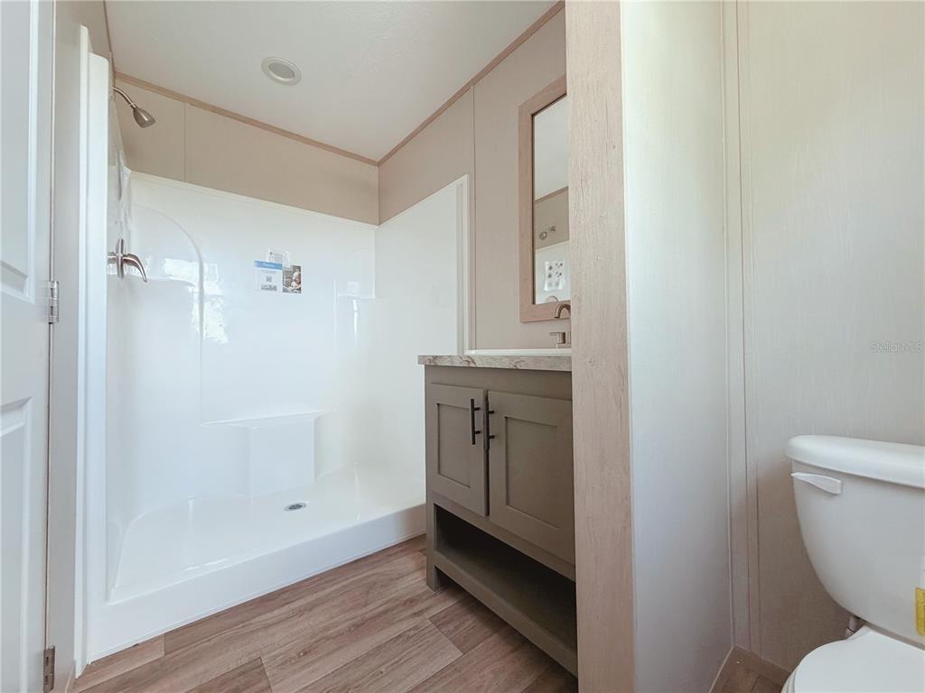 A bathroom features a walk-in shower, a gray vanity with a mirror, and a toilet — 2861 FAST TROT TRAIL, LAKE WALES, FL