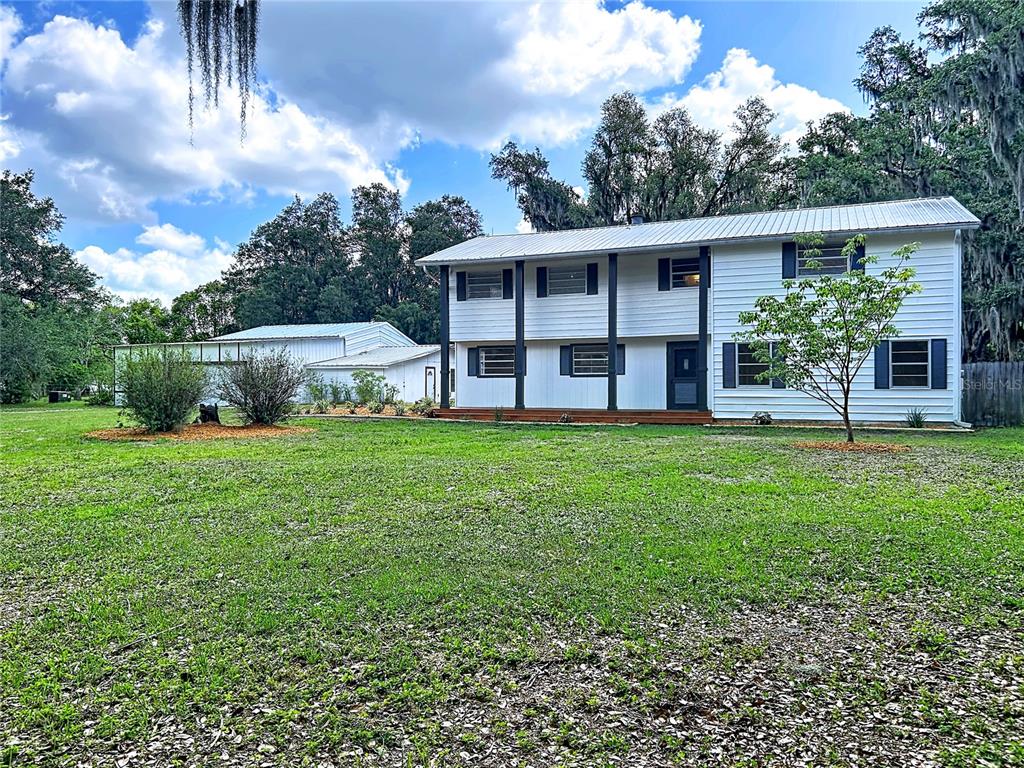 A two-story white house with a metal roof stands behind a large grassy yard — 11008 BROWNING ROAD, LITHIA, FL