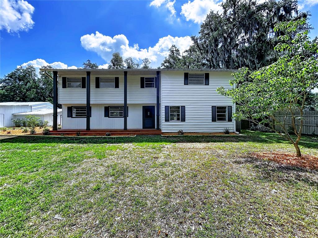 A two-story white house with a covered front porch and dark shutters stands outdoors — 11008 BROWNING ROAD, LITHIA, FL