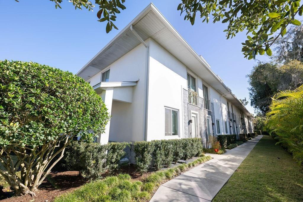 A white multi-story townhouse exterior features a sidewalk, manicured hedges, and a clear blue sky — 432 W SWOOPE AVENUE, WINTER PARK, FL