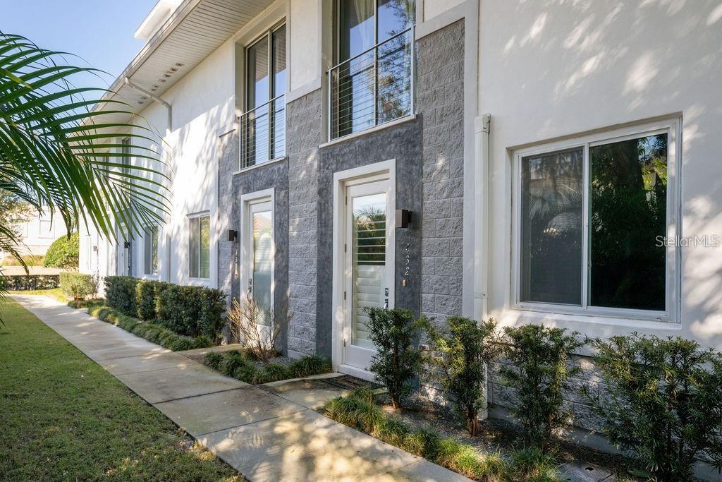 A view of a two-story townhouse exterior with a concrete walkway and landscaped bushes — 432 W SWOOPE AVENUE, WINTER PARK, FL