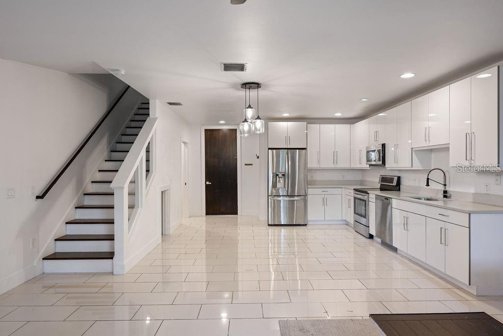 A modern kitchen with white cabinetry and stainless steel appliances sits beside a staircase — 432 W SWOOPE AVENUE, WINTER PARK, FL