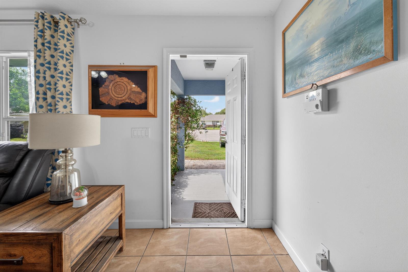 An entryway features tile flooring, a wooden console table, and an open door to outside — 706 Osceola Avenue, Fort Pierce FL 34982, FORT PIERCE, FL