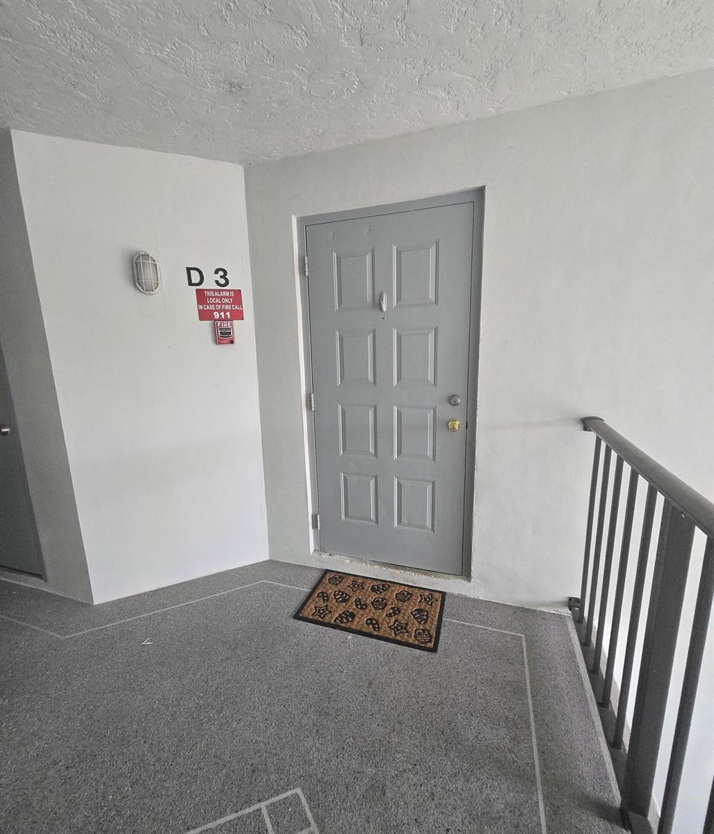 An exterior view of an apartment entrance with a grey door and a welcome mat — 1009 Green Pine Boulevard # D3, West Palm Beach FL 33409, WEST PALM BEACH, FL