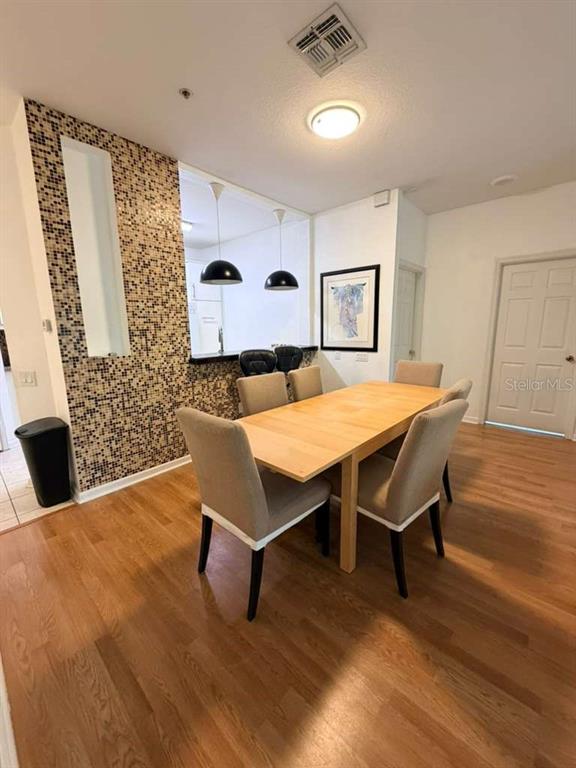 A dining area features a wooden table, four upholstered chairs, and a mosaic-tiled accent wall — 6214 STEVENSON DRIVE UNIT 303, ORLANDO, FL