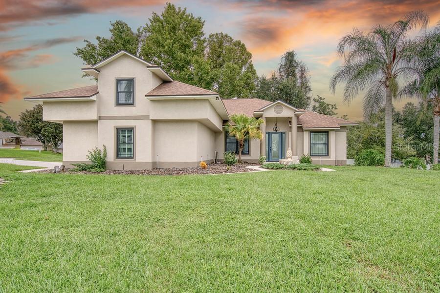A two-story house with a beige stucco exterior, a shingled roof, and a grassy lawn — 10537 VERSAILLES BOULEVARD, CLERMONT, FL