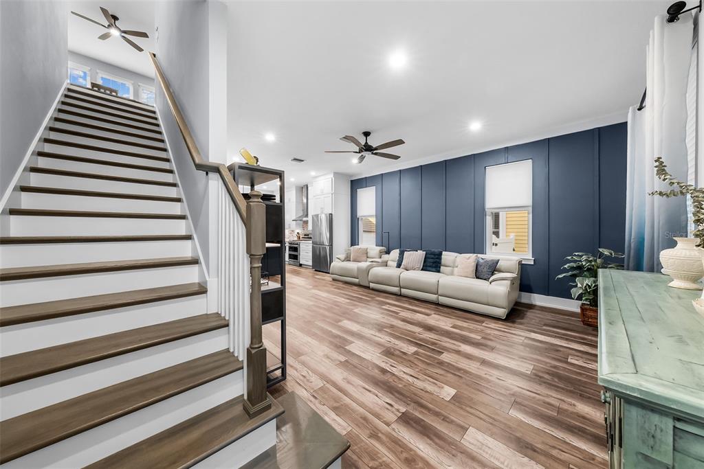 A staircase with wooden treads leads to an open living area featuring a blue accent wall — 607 12TH AVENUE S, ST PETERSBURG, FL