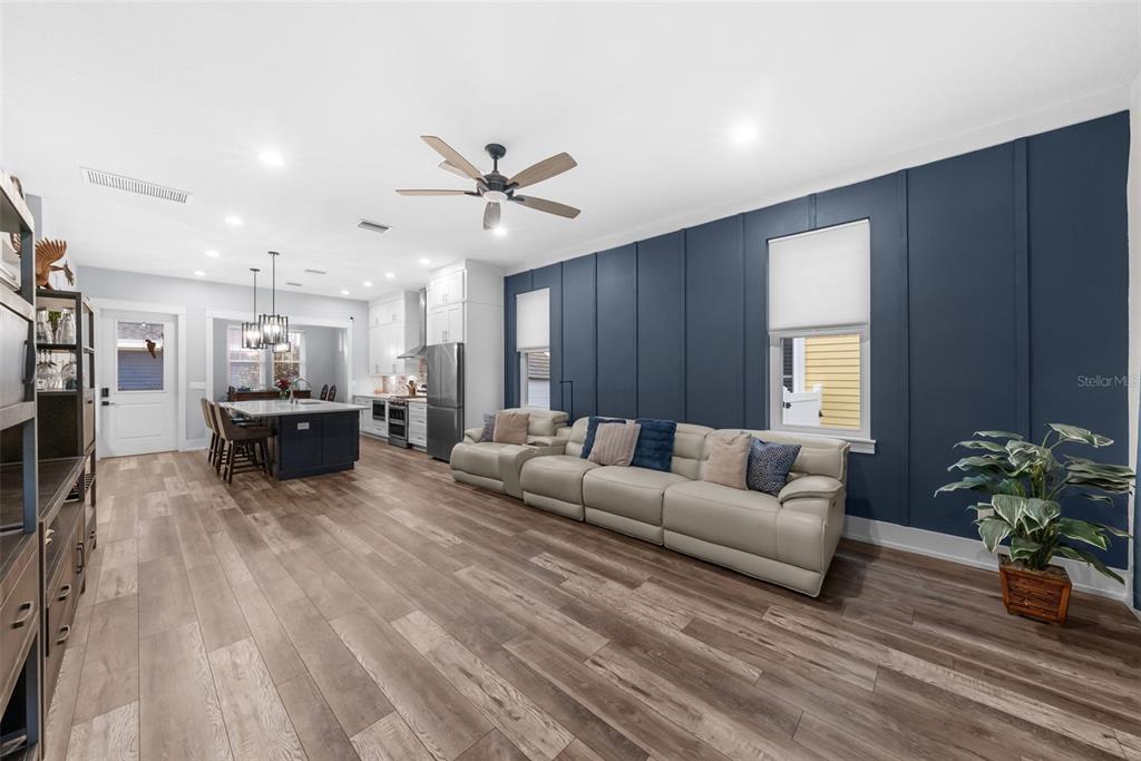 A living room with wood-look flooring, a large grey sectional, and a dark blue accent wall — 607 12TH AVENUE S, ST PETERSBURG, FL