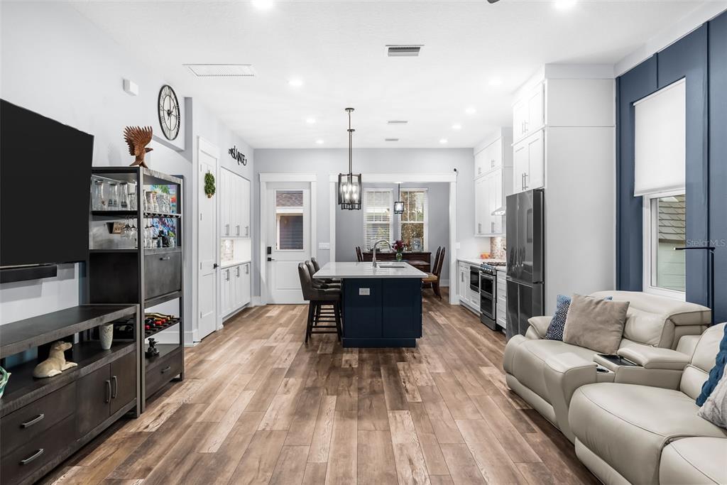 An open-concept kitchen and living area features a dark blue island, white cabinetry, and wood-look flooring — 607 12TH AVENUE S, ST PETERSBURG, FL