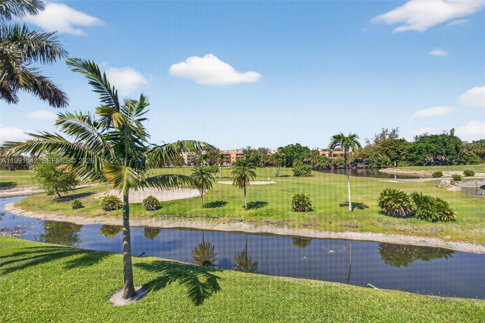 A view of a golf course with a small canal, palm trees, and sand bunkers — 4299 NW 16th St # 202, Lauderhill FL 33313, LAUDERHILL, FL