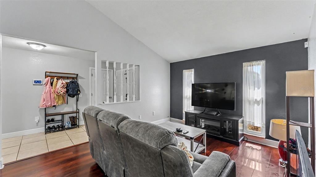 A living room features a grey sofa, dark wood flooring, and a dark accent wall — 5060 STARLING DRIVE, MULBERRY, FL