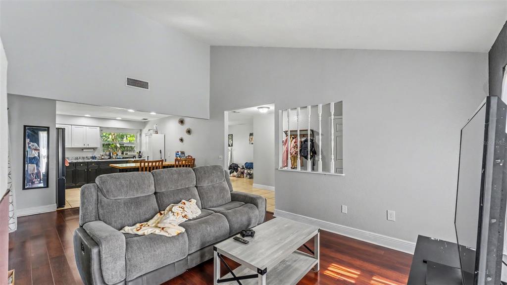 A living room with a grey sofa, wood floors, and a partial wall with spindles — 5060 STARLING DRIVE, MULBERRY, FL