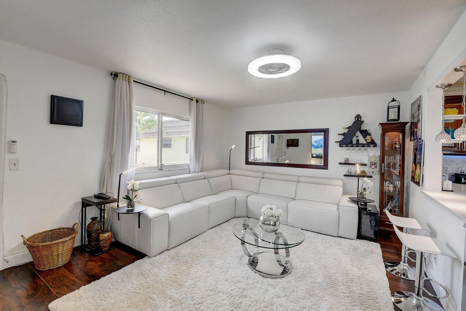 A living room with a white sectional sofa, glass coffee table, and white area rug — 123 Saxony C, Delray Beach FL 33446, DELRAY BEACH, FL