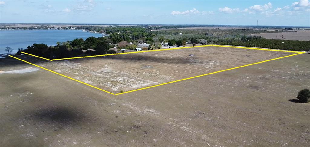 An aerial view shows a large, flat, rectangular plot of land outlined in yellow — 100 CLOVERLEAF ROAD, LAKE PLACID, FL