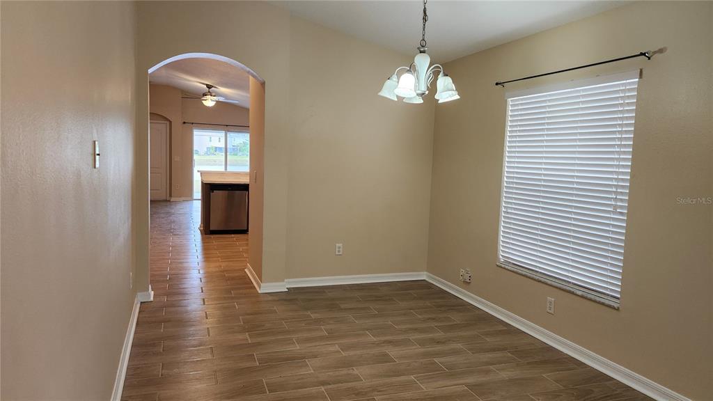A dining area with wood-look tile flooring, a chandelier, and an arched entryway to a kitchen — 7955 CARRIAGE POINTE DRIVE, GIBSONTON, FL