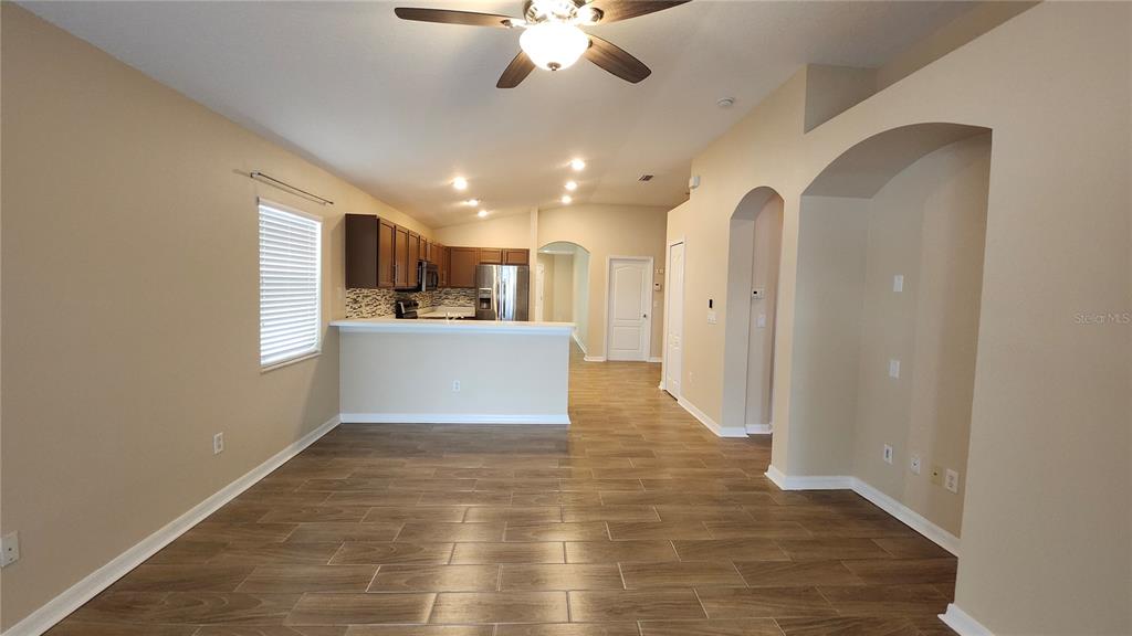 A living area with wood-look tile flooring leads to an open kitchen with dark cabinets — 7955 CARRIAGE POINTE DRIVE, GIBSONTON, FL