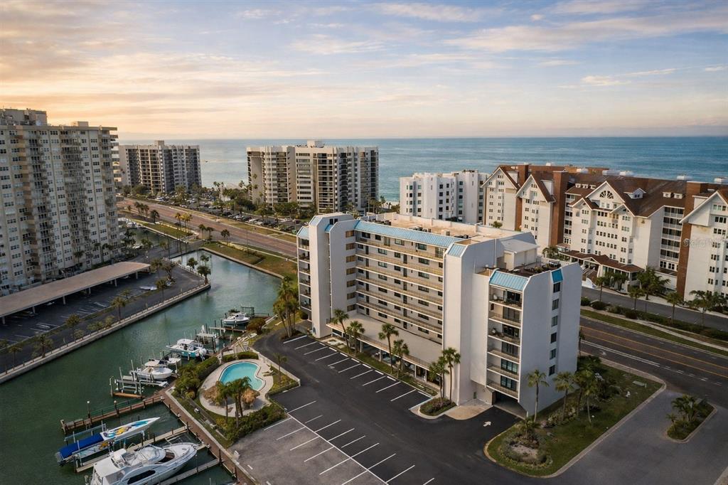 An aerial view of a multi-story waterfront condominium complex with a boat dock and pool — 1591 GULF BOULEVARD UNIT 203S, CLEARWATER BEACH, FL