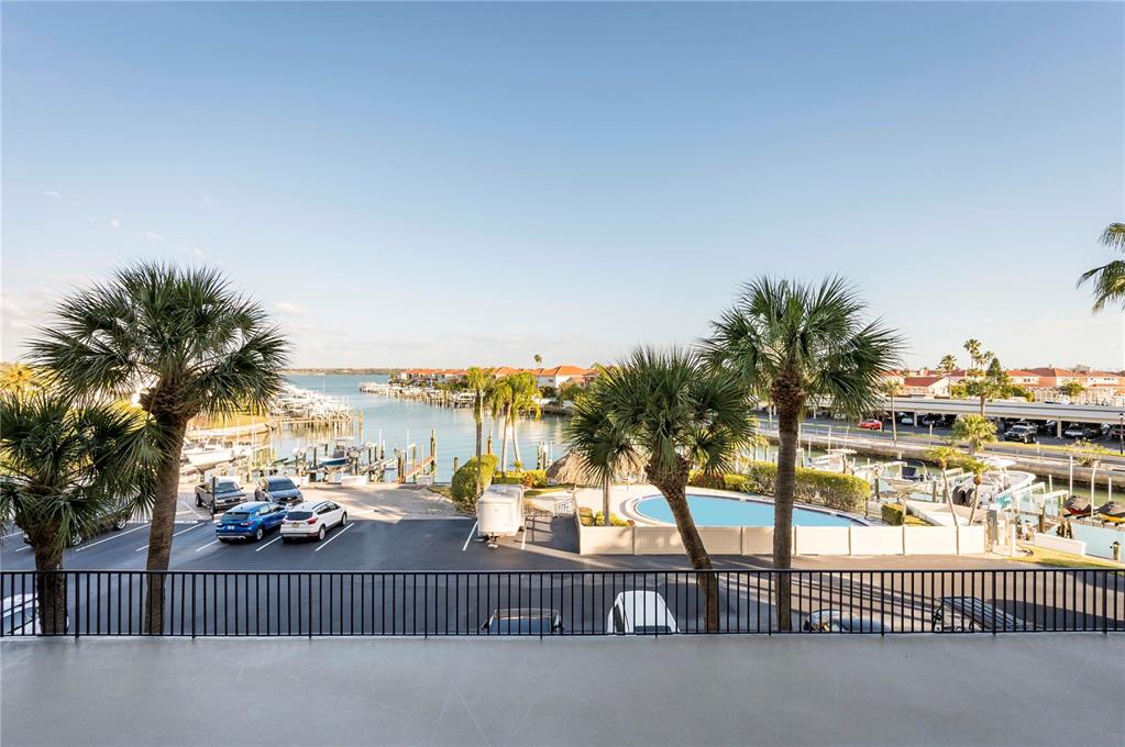 A balcony overlooks a parking lot, a swimming pool, and a marina with boats — 1591 GULF BOULEVARD UNIT 203S, CLEARWATER BEACH, FL