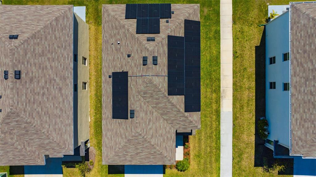 An aerial view shows three houses with shingled roofs, one featuring solar panels — 5758 HOLLINGWORTH TRAIL, WESLEY CHAPEL, FL