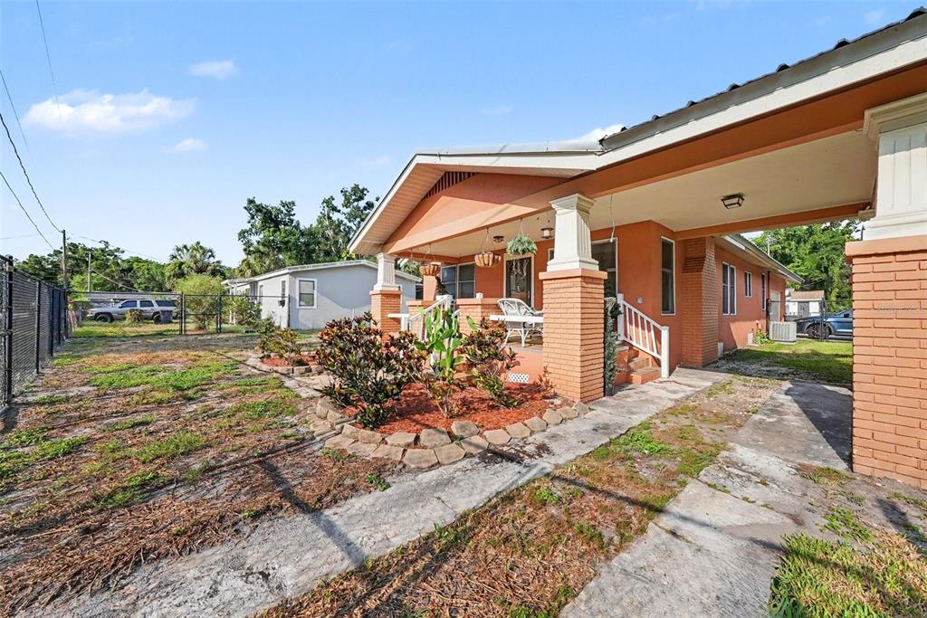 An orange house with a brick-columned porch and a concrete driveway sits on a lot — 9907 MAGGIE STREET, GIBSONTON, FL