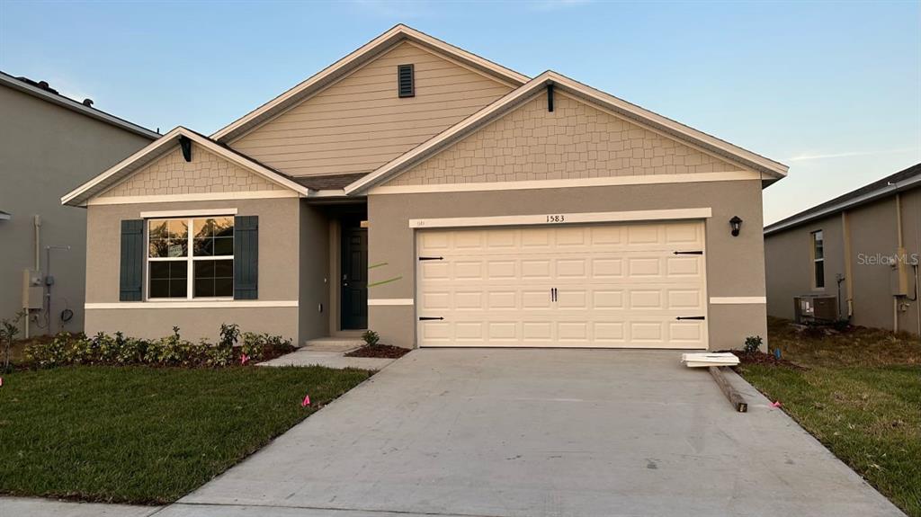 A single-story house with a gray stucco exterior, a two-car garage, and a front window — 1583 BARBERRY DRIVE, KISSIMMEE, FL