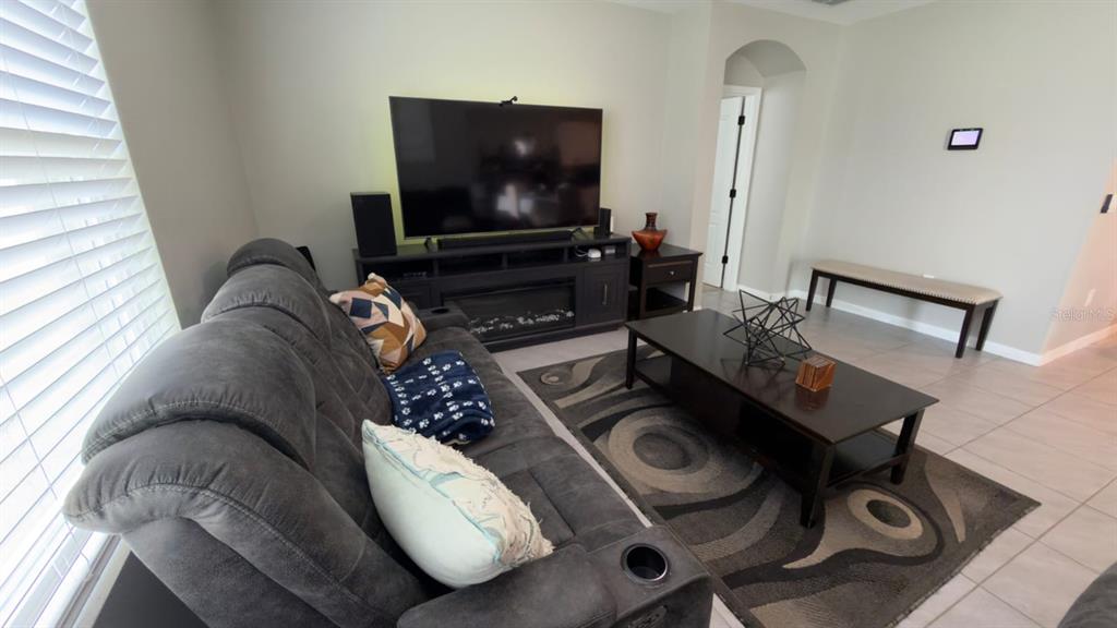 A living room features a gray reclining sofa, a dark media console, and a coffee table — 1583 BARBERRY DRIVE, KISSIMMEE, FL