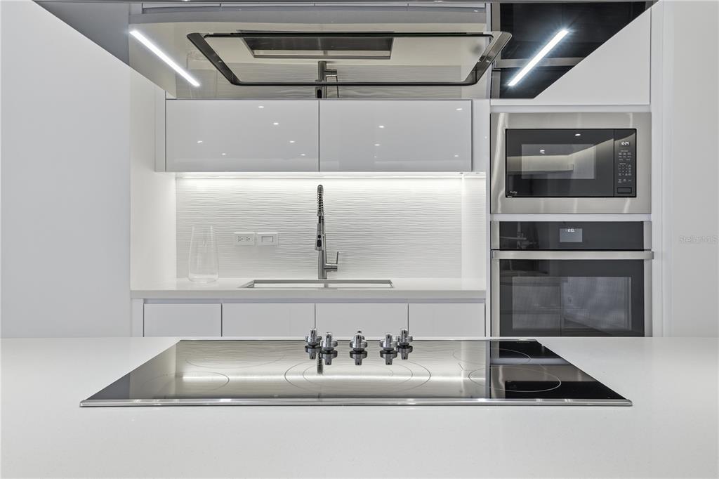 A modern kitchen features white cabinetry, a stainless steel oven, and a central induction cooktop — 3307 ISLA VERDE AVE. UNIT 1, CAROLINA, PR