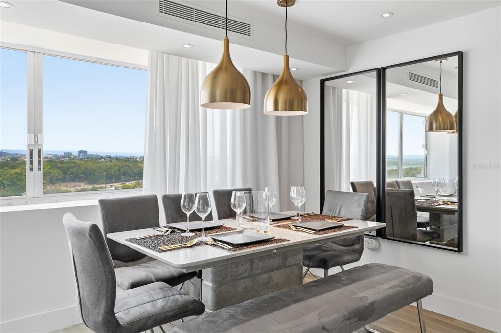 A dining room features a stone table, gray upholstered chairs, gold pendant lights, and mirrors — 3307 ISLA VERDE AVE. UNIT 1, CAROLINA, PR