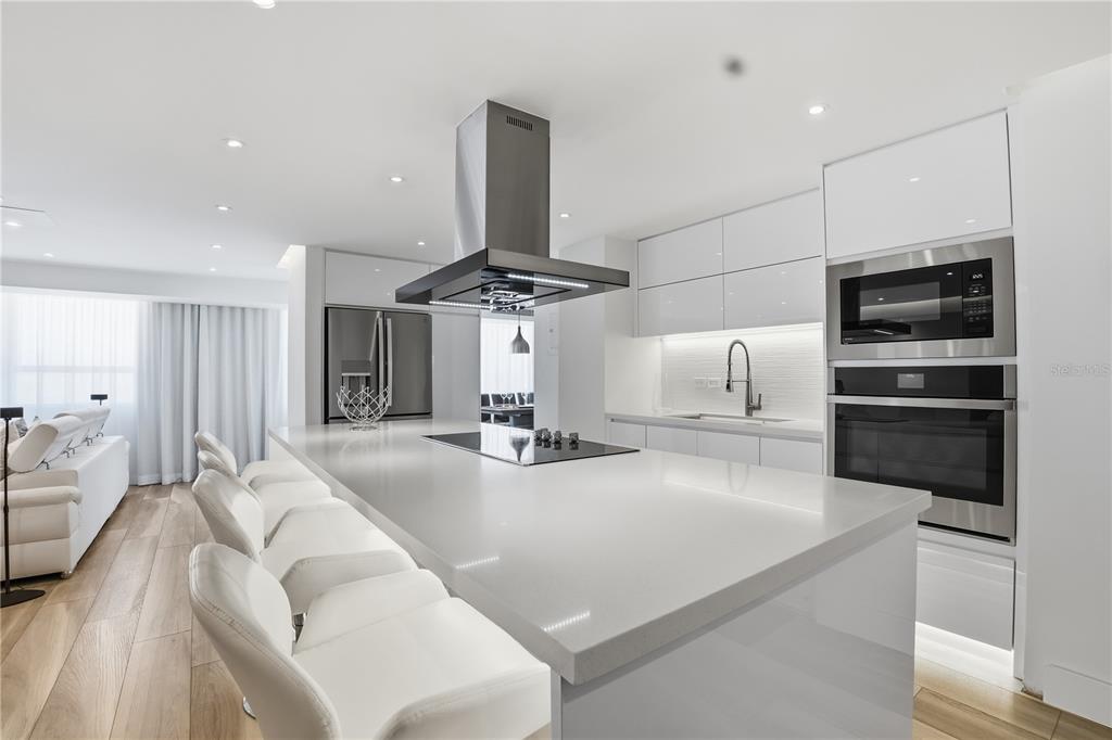 A modern white kitchen features a large island with a cooktop and bar seating — 3307 ISLA VERDE AVE. UNIT 1, CAROLINA, PR