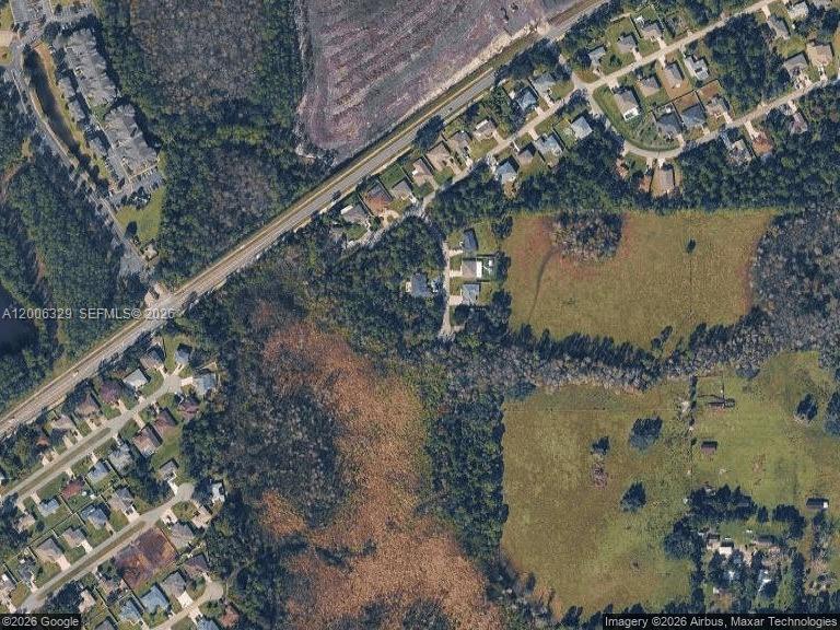 This aerial view shows a residential neighborhood bordering a large, undeveloped wooded and grassy area — 8 Slogan CT, Palm Coast FL 32164, PALM COAST, FL