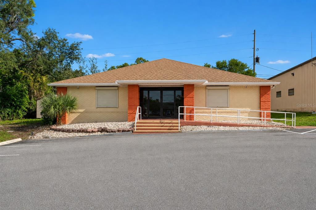 A single-story brick commercial building features a central entrance with stairs and a wheelchair ramp — 10507 SPRING HILL DRIVE, SPRING HILL, FL