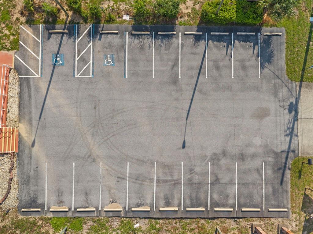 An aerial view shows a paved parking lot with marked spaces, including two handicap-accessible spots — 10507 SPRING HILL DRIVE, SPRING HILL, FL