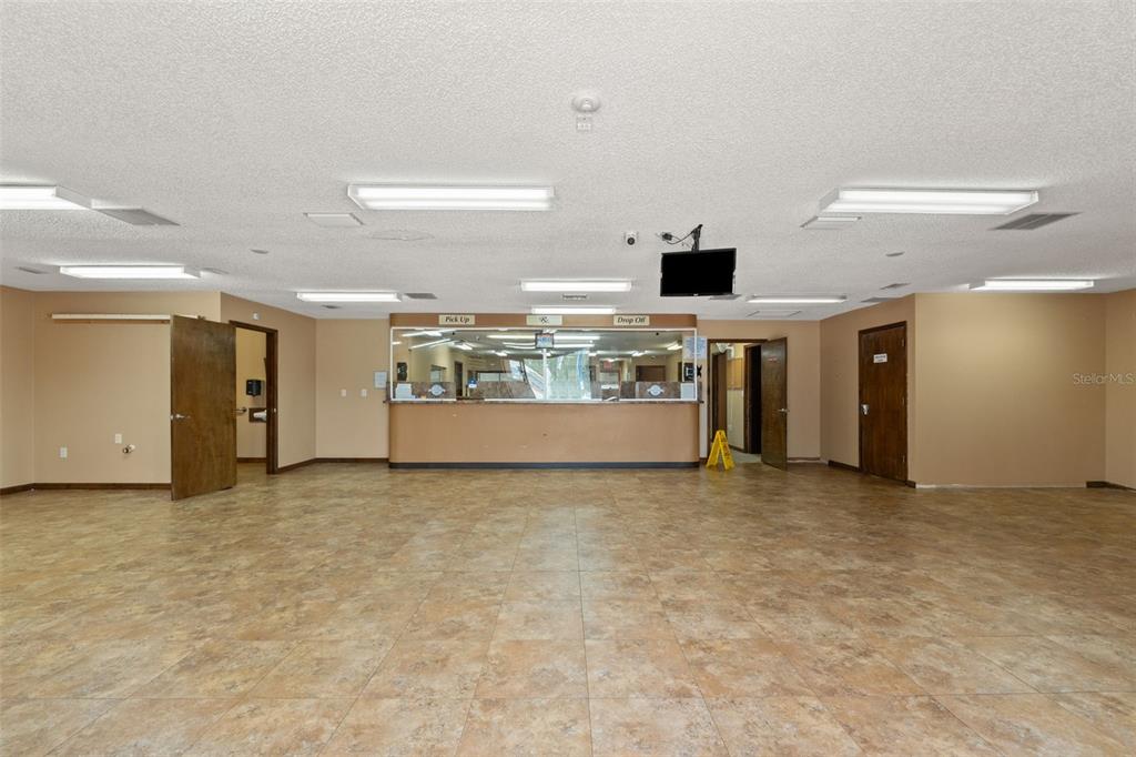 An empty commercial office space features a reception counter, tile flooring, and drop ceiling lights — 10507 SPRING HILL DRIVE, SPRING HILL, FL