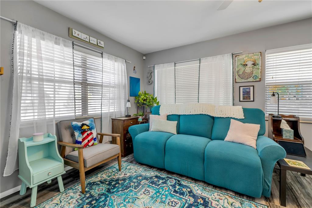 A living room features a teal sofa, a gray armchair, and a patterned area rug — 2805 SAXON DRIVE, NEW SMYRNA BEACH, FL