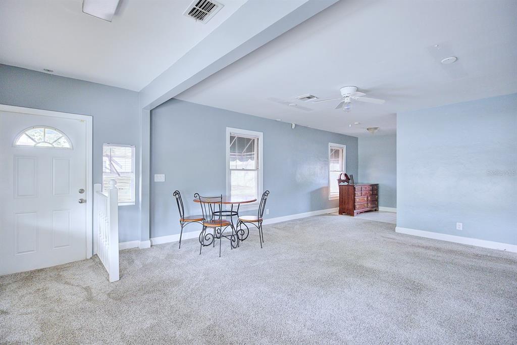 A spacious room with light blue walls, gray carpeting, a dining set, and white trim — 121 BATES AVENUE SE, WINTER HAVEN, FL