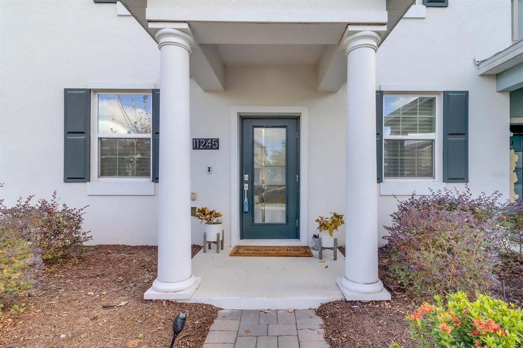 The front entrance of a house features a glass-paneled door between two white columns — 11245 LISTENING DRIVE, ORLANDO, FL