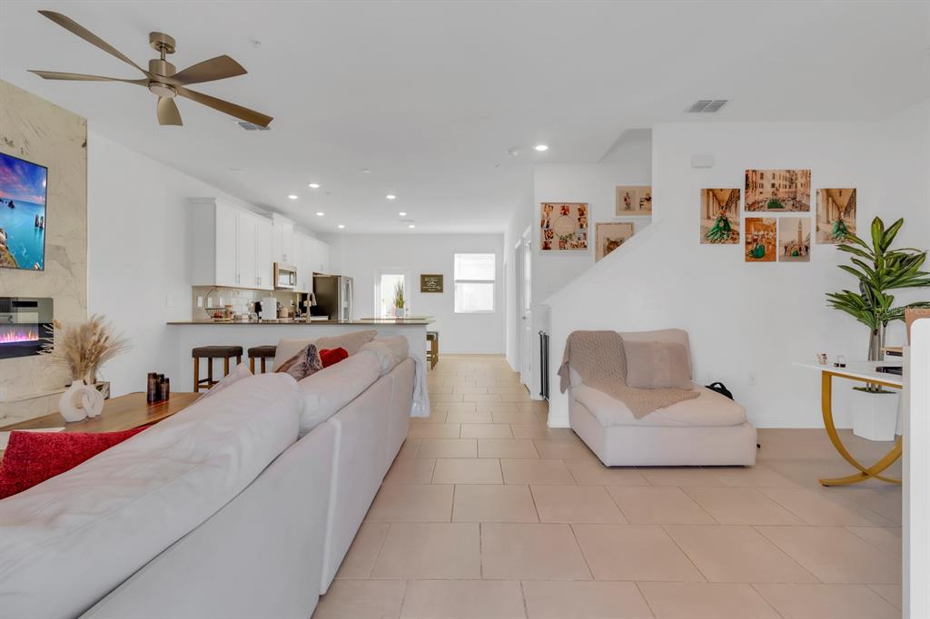 A living room with light tile floors, a white sofa, and an open kitchen beyond — 11245 LISTENING DRIVE, ORLANDO, FL