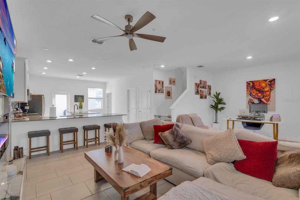 An open-concept living room features a large sectional sofa, a wooden coffee table, and kitchen — 11245 LISTENING DRIVE, ORLANDO, FL