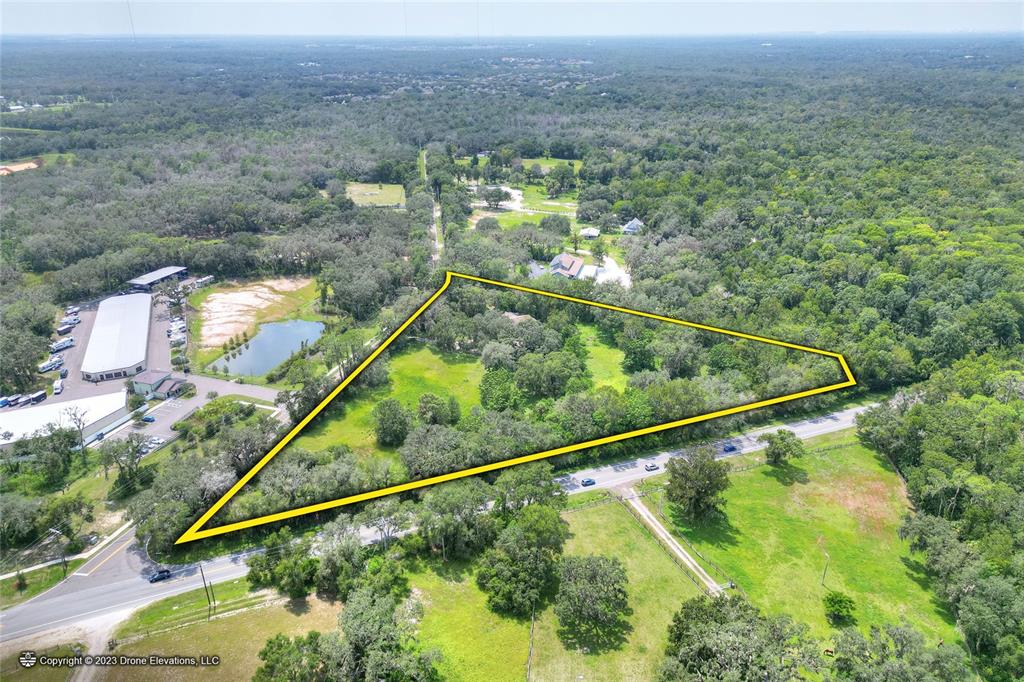 An aerial view shows a triangular plot of land bordered by roads and dense trees — 5226 LITHIA SPRINGS ROAD, LITHIA, FL