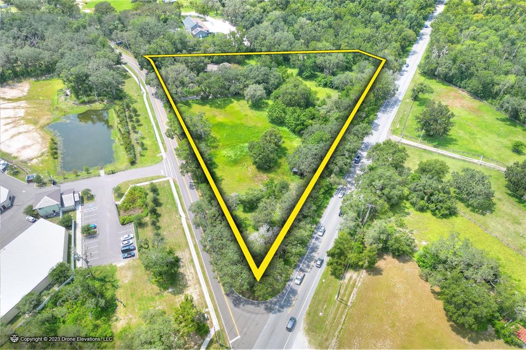 An aerial view shows a triangular plot of land bordered by two roads and trees — 5226 LITHIA SPRINGS ROAD, LITHIA, FL