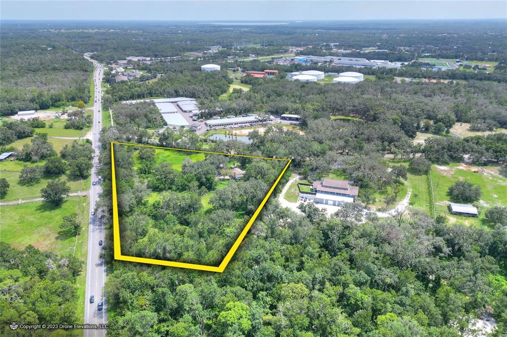 An aerial view shows a wooded lot outlined in yellow next to a paved road — 5226 LITHIA SPRINGS ROAD, LITHIA, FL