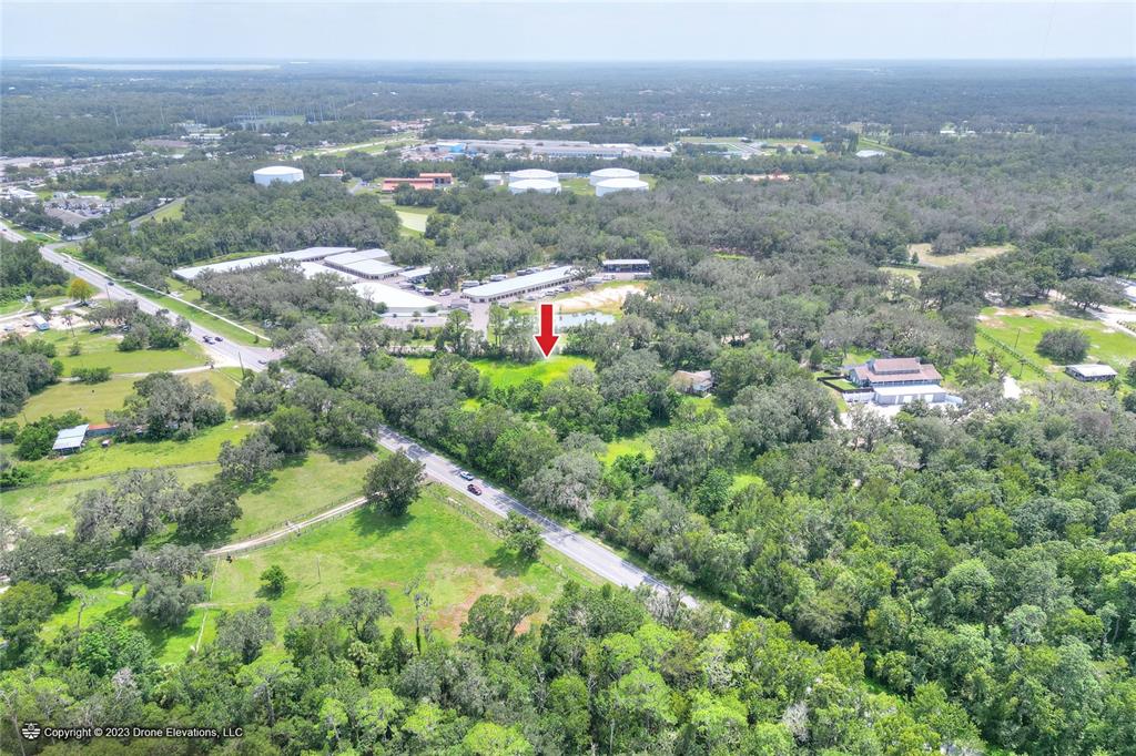 An aerial view shows a grassy lot marked by a red arrow near a road — 5226 LITHIA SPRINGS ROAD, LITHIA, FL
