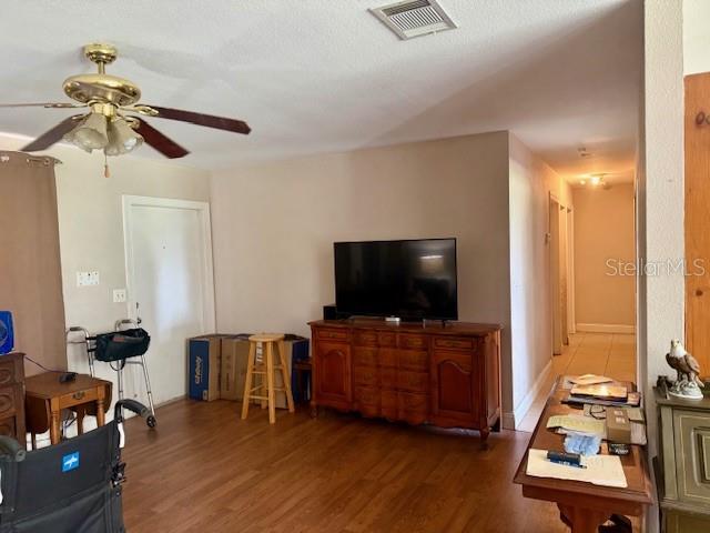 A living room with wood-look flooring, a ceiling fan, a television, and a wooden console — 7186 GURLEY COURT, NORTH PORT, FL