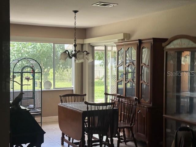 A dining area features a wooden table, chairs, a hutch, and a birdcage near windows — 7186 GURLEY COURT, NORTH PORT, FL